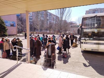 People stand near a bus preparing to evacuate unnamed Jewish community in Ukraine