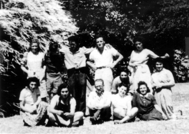 A group of young adults sitting and standing in front of trees
