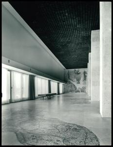 A gallery with a bench, a floor mosaic, and a wall mosaic of a menorah