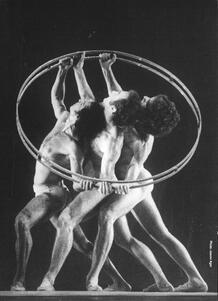 Three men in identical poses, holding a large circular prop around them
