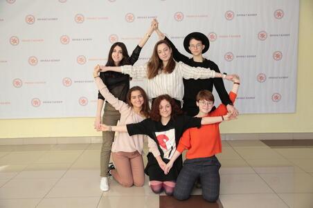 Six young women standing and kneeling, with their arms stretched in the shape of a star of David