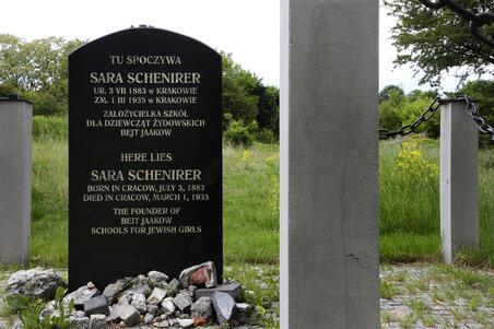 A tall black tombstone with stones piled at the bottom