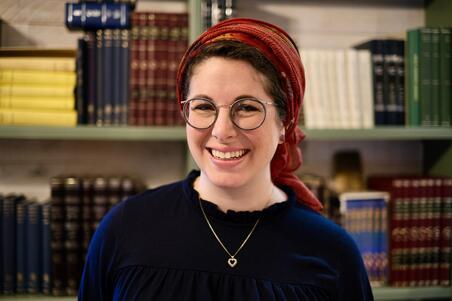 Rabbanit Leah Sarna wearing head covering, navy blue shirt, heart necklace