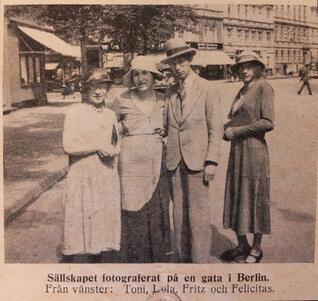 Black and white historical photograph of three women and a man standing in a city street