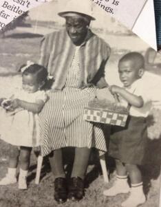 Black and white photo of Black woman sitting with grandchildren on either side of her