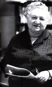black and white photograph of an older woman with white hair holding a newspaper