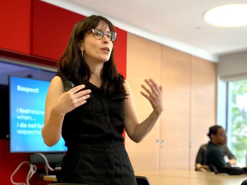 Woman talking and standing in front of slide presentation