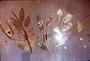 An abstract metal sculpture of gold-colored branches and leaves made out of triangles, mounted on a wooden wall