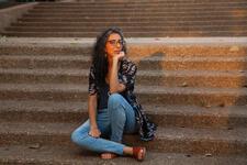 photo of a woman with long curly hair sitting on outdoor stairs