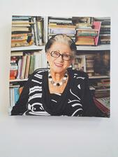 Photograph of a woman in a black and white dress in front of a bookshelf