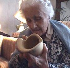 photograph of a woman with white hair working on pottery