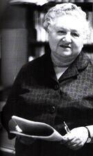 black and white photograph of an older woman with white hair holding a newspaper