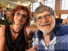 photograph of a woman with short curly red hair and a man with light brown hair and a beard