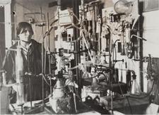 black and white photograph of a woman in a lab surrounded by lab equipment