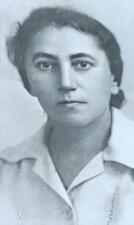 black and white photograph of a woman with dark hair pulled back, looking seriously at the camera
