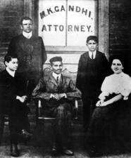 Sonja Schlesin with Gandhi and three others in front of a window reading M.K. Gandhi Attorney