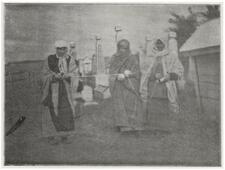 black and white historial photograph of women in robes and head scarves measuring a grave