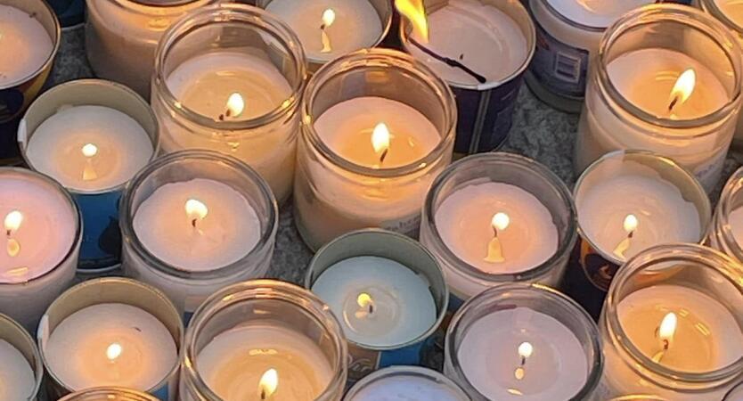 About 30 lit yahrzeit candles on the ground