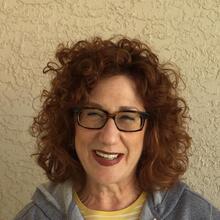 photograph of a woman with red hair and glasses smiling