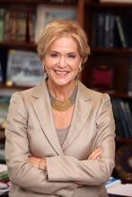 photograph of a woman with blond hair in a tan suit