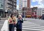 Two women talk while crossing the street