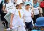 Two women wearing white and marching  holding a sign that says "Women Wage Peace" in English, Hebrew, and Arabic