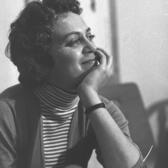 Hanna Maron sitting at a table, smiling with her chin in her hand