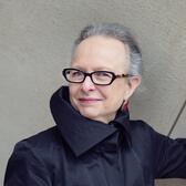 Barbara Kirshenblatt-Gimblett smiling, wearing a black, high collar top and glasses