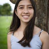 Photo of Maddy Pollack, in front of a tree wearing a grey shirt.