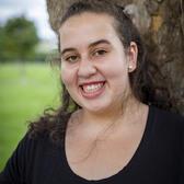 Photo of Ellie Klibaner-Schiff, in front of a tree wearing a black shirt.