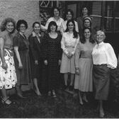 A group of eleven women posing together in a courtyard