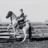 Frances Kallison and horse posed in front of wooden fence
