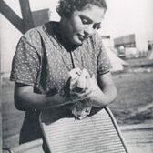 A woman washes laundry by hand with a tin tub and washboard.