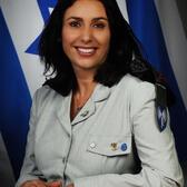 Miri Regev seated in front of an Israeli flag, wearing decorated uniform.