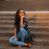 photo of a woman with long curly hair sitting on outdoor stairs