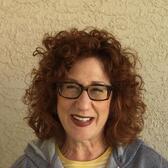 photograph of a woman with red hair and glasses smiling