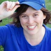 Jessie Atkin wearing blue t-shirt and blue baseball cap posing in front of grass