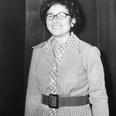 black and white photograph of a woman with short dark hair wearing a checked dress