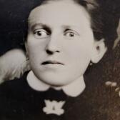 black and white historical photo of a woman in a black dress with a white collar