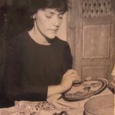 Black and white photograph of a woman embroidering a challah cover