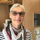 Doris Gray Headshot - Woman with short white hair, glasses, striped shirt