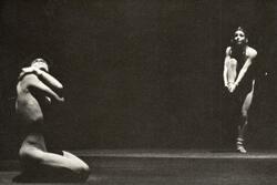 Cecilia Baram dancing, balancing on one foot, while Miguel Angel Palmeros kneels on the other side of the stage