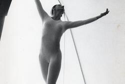 Cecilia Baram dancing on a bench, wearing a long-sleeved leotard with her arms lifted in the air