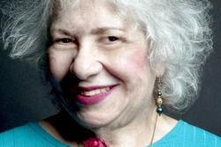 Aviva Cantor wearing a blue shirt holding a rose and smiling to the camera
