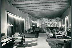 A hotel lobby with seating and rugs, and a painted mural