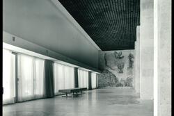 A gallery with a bench, a floor mosaic, and a wall mosaic of a menorah