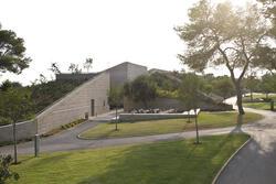 An angular stone building surrounded by trees and grass