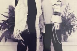 Two women smiling at the camera, gesturing happily and wearing prayer shawls