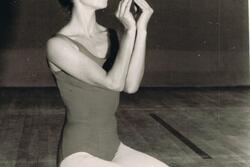 Ruth Eshel kneeling on a stage with her hands cupped in an oval shape