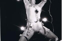 Ruth Eshel with arms and legs spread wide, wearing a number of light bulbs on belts attached to her limbs and torso